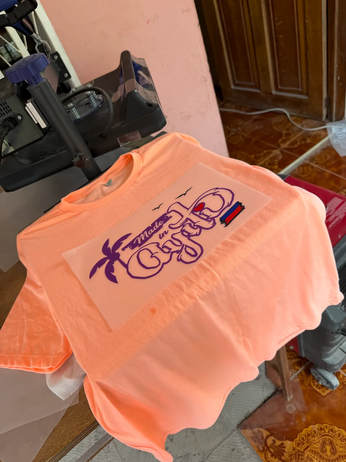T-shirt orange Made in Ayiti sous la presse, film de transfert encore visible